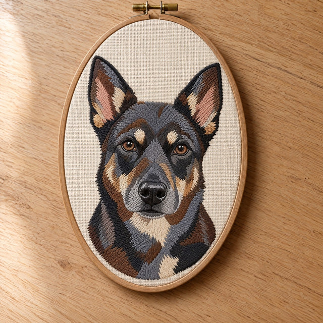 Embroidered portrait of a black-faced dog, the dark coat built from charcoal, brown and slate thread